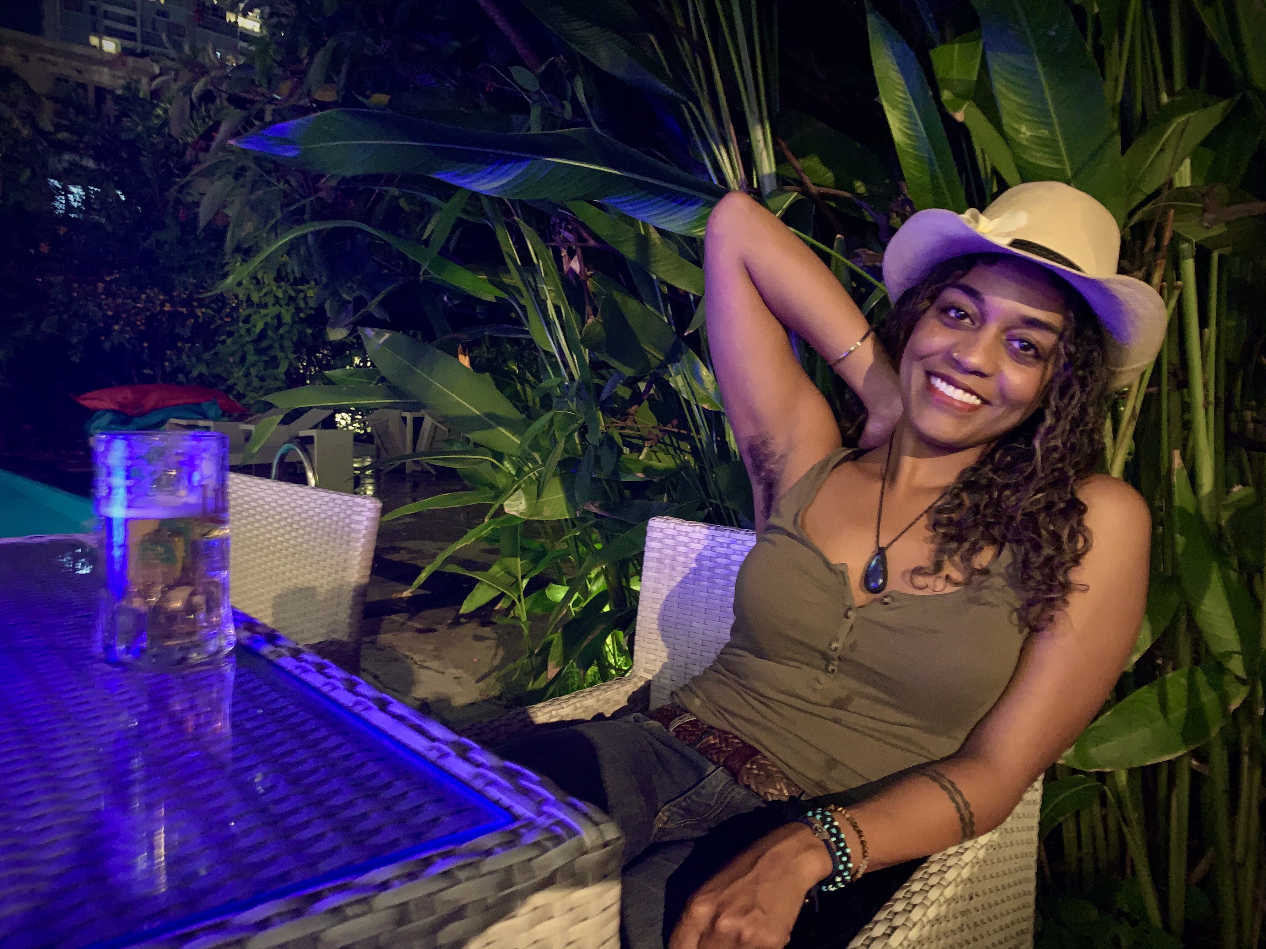 Amanda raises right arm exposing her armpit near a pool at night 