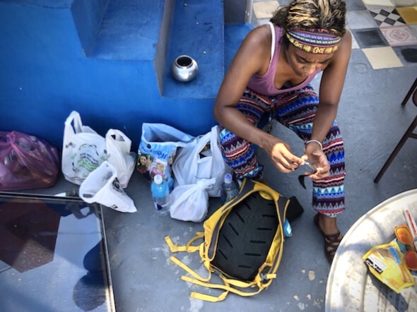 Amanda sites on the floor of the hostel’s rooftop terrace as she goes through an item in her bag. She  has a very  angry expression. 