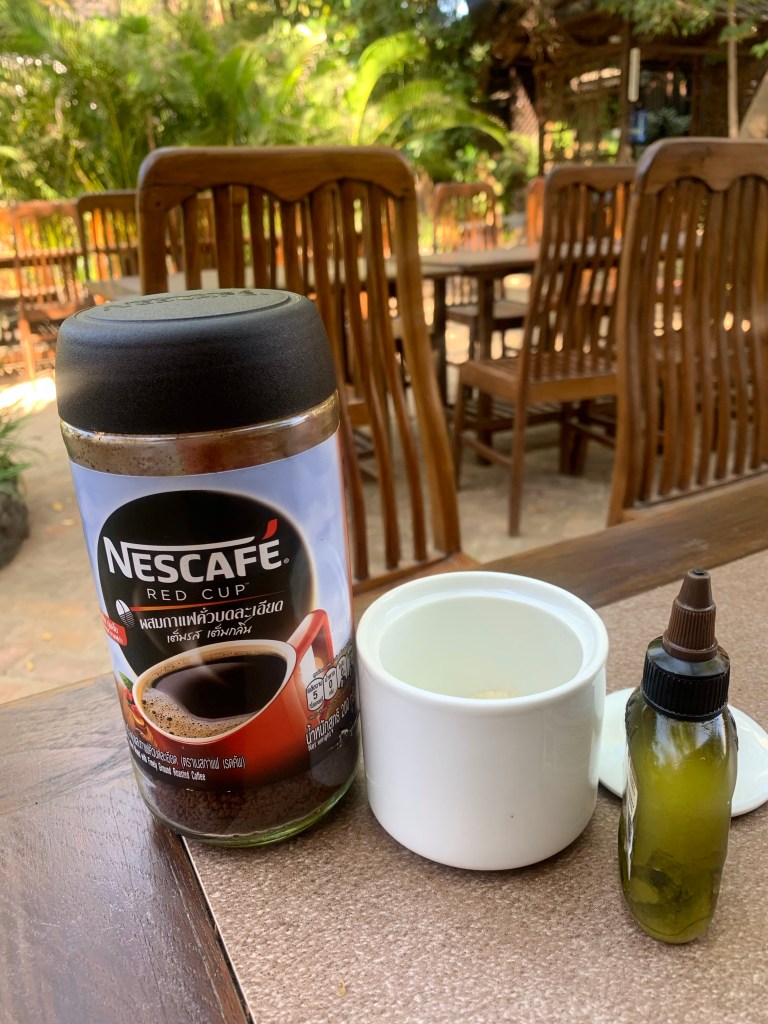 Coffee, white sugar and a bottle of coconut oil on a table.